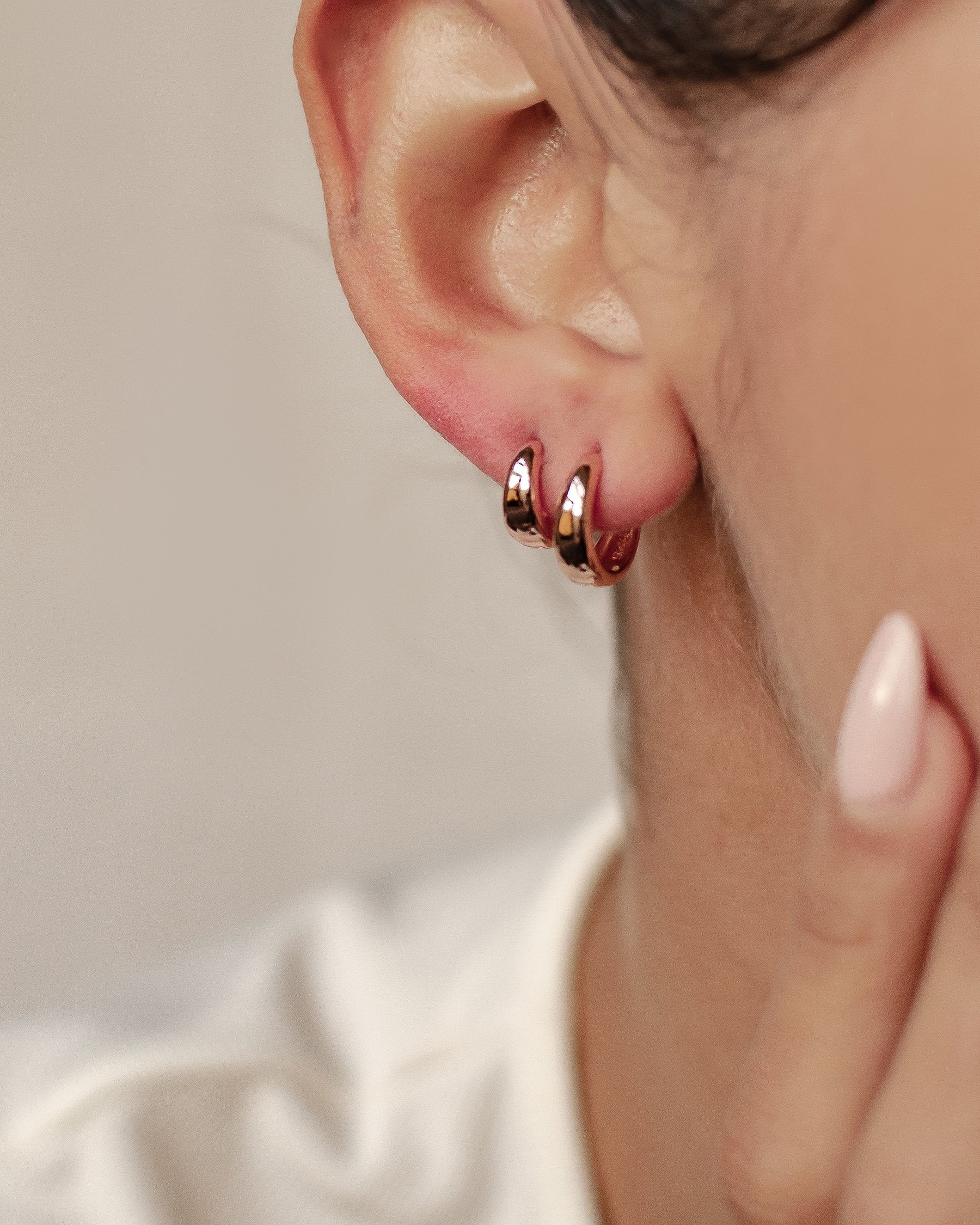 Rose gold chunky hoop earrings stacked on an ear