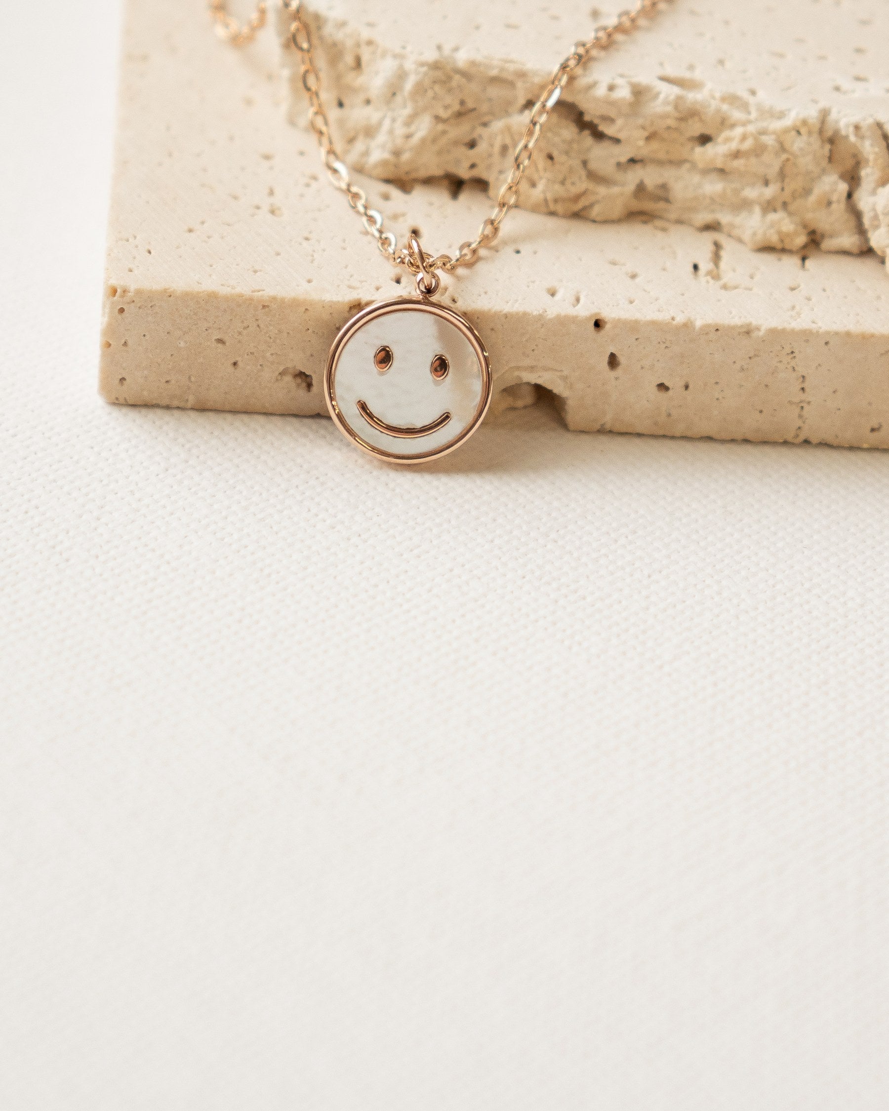 Smiley face pendant necklace on a stone block